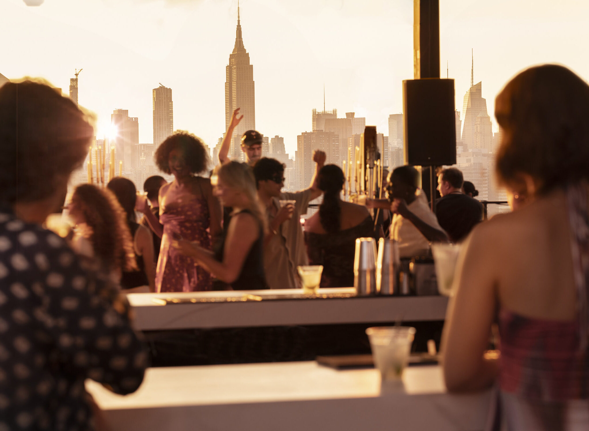 Group of people chilling at ART williamsburg rooftop bar overlooking the Empire State Building